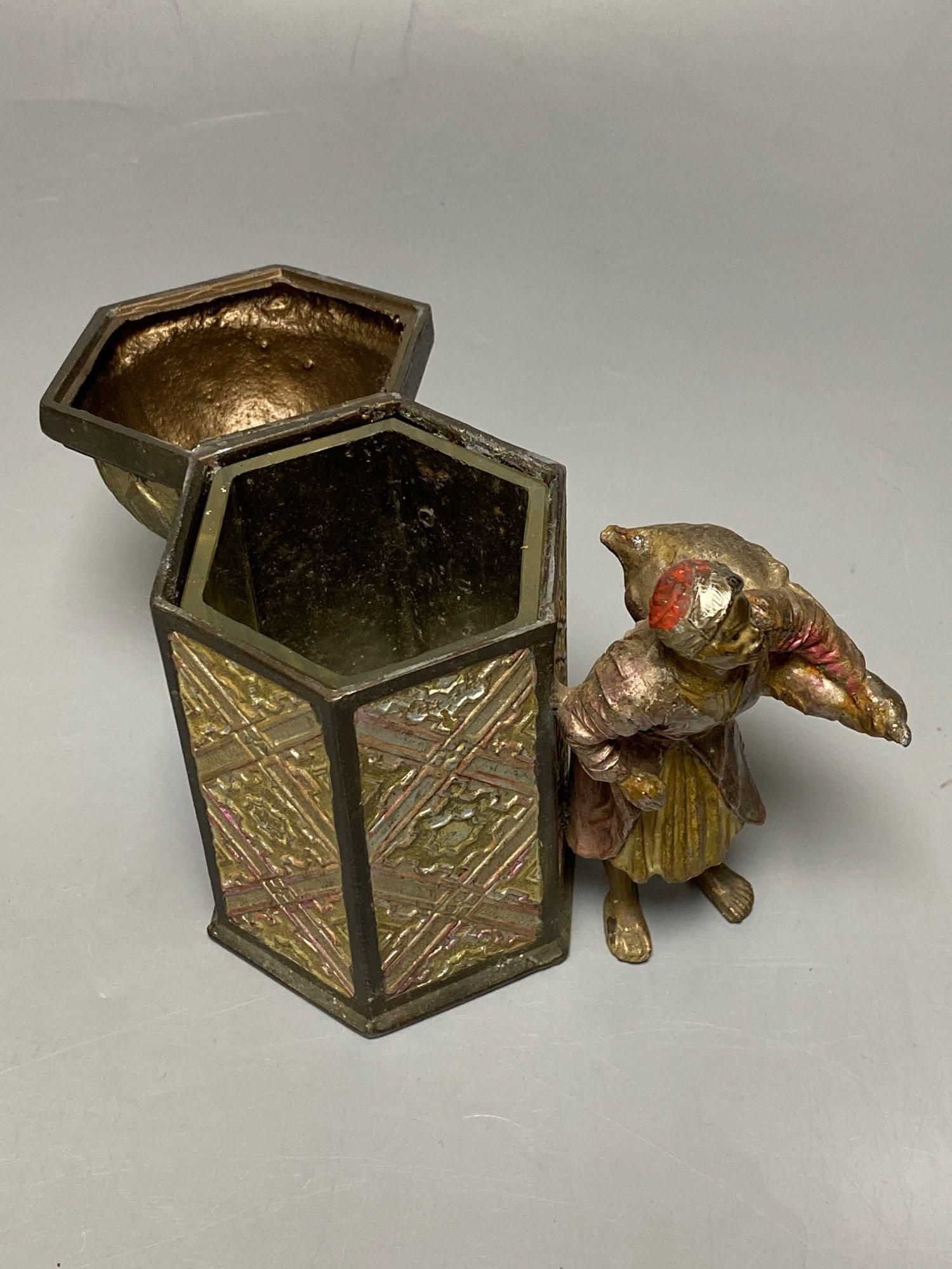 A Bergman style cold painted metal hexagonal casket, with hinged cover, Itinerant labourer alongside, 15cm